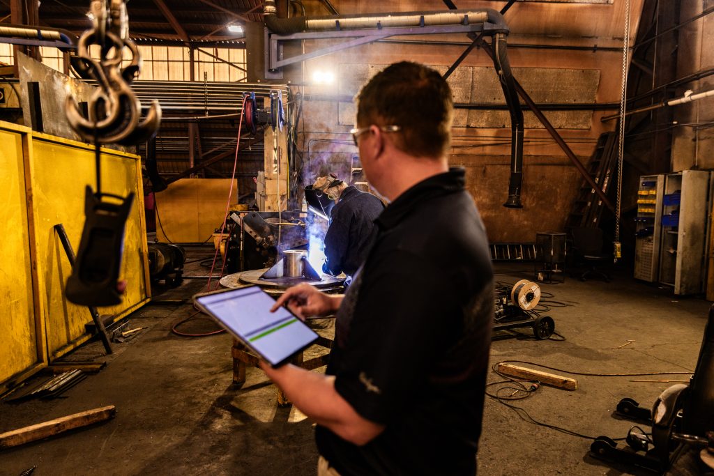 Man in industrial plant using crewOS to schedule field service jobs.