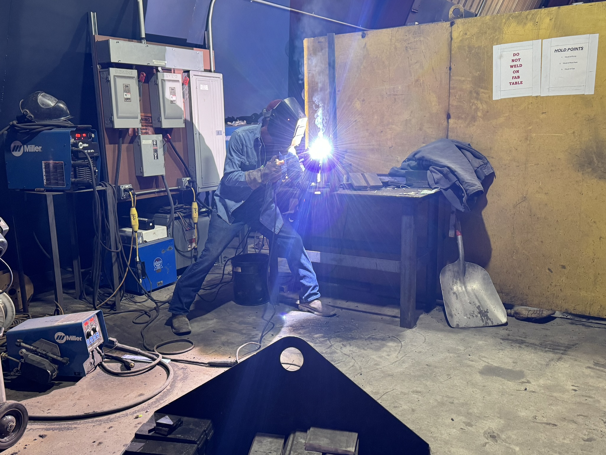 Industrial field service crewman welding in a warehouse.
