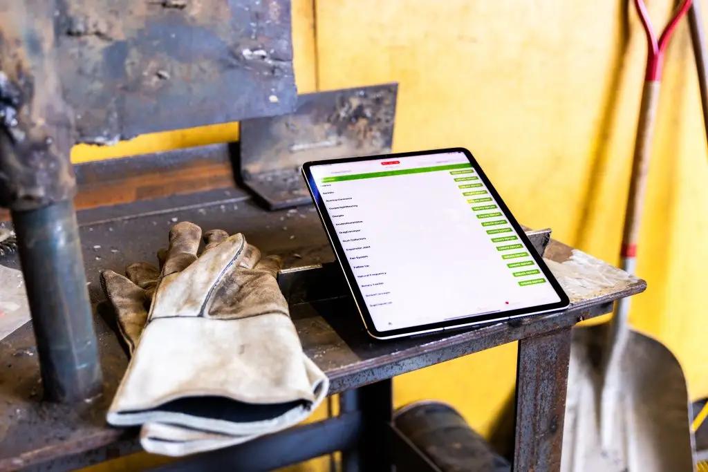crewOS industrial field service app on an iPad in an industrial environment beside work gloves