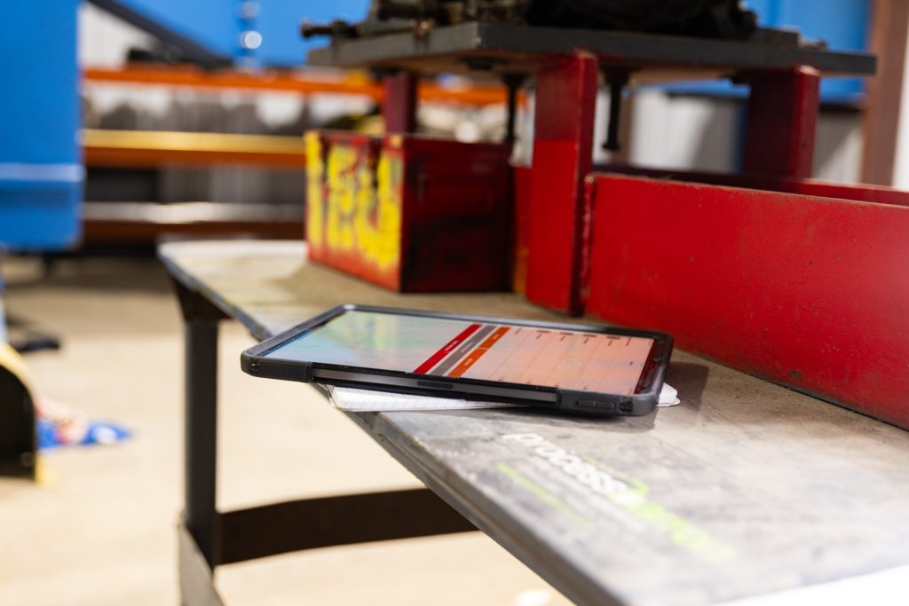 crewOS industrial field service management app on an iPad on a workbench in an industrial environment