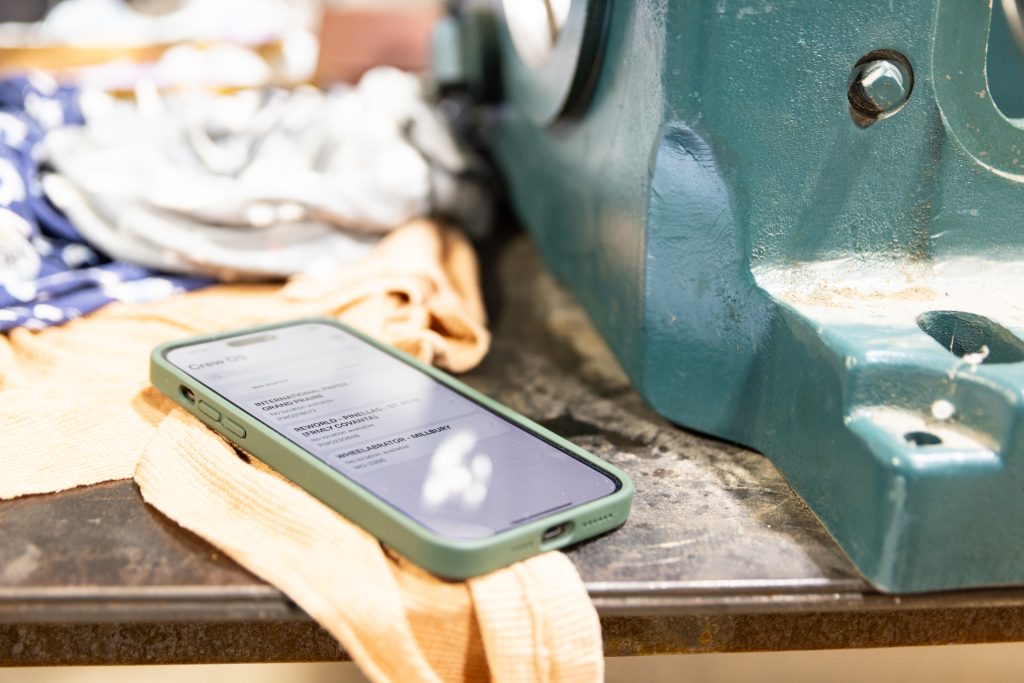 crewOS Industrial Field Service Software on iPhone in a manufacturing plant
