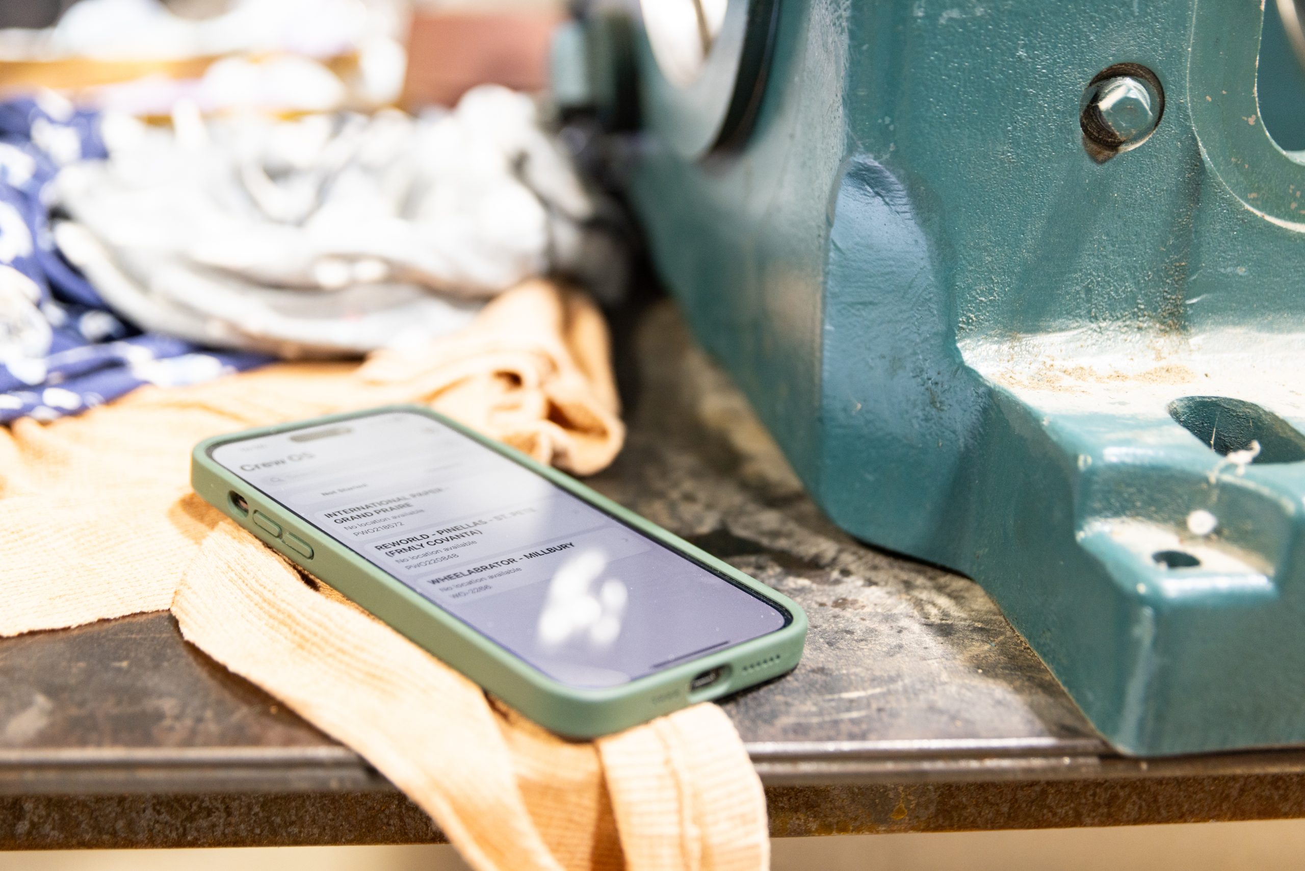 A phone with crewOS open in the industrial field service space.